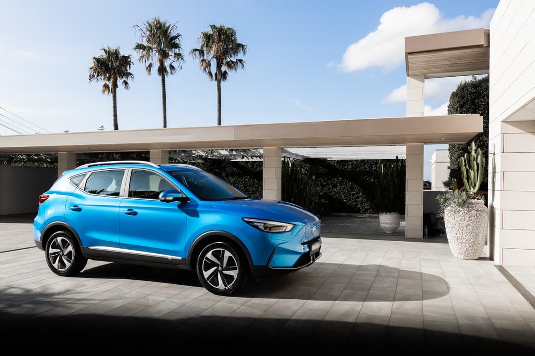 Blue MG ZS EV in front of modern home driveway Blue MG ZS EV in front of modern home driveway
